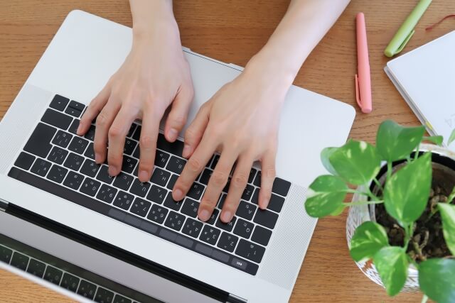 ノートパソコンでタイピングする手